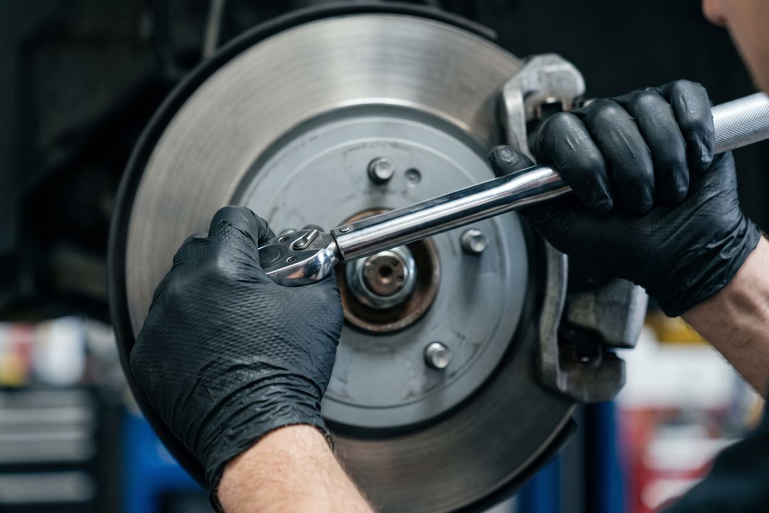 Gloved hands torquing a lug nut on a clean brake rotor with a chrome torque wrench